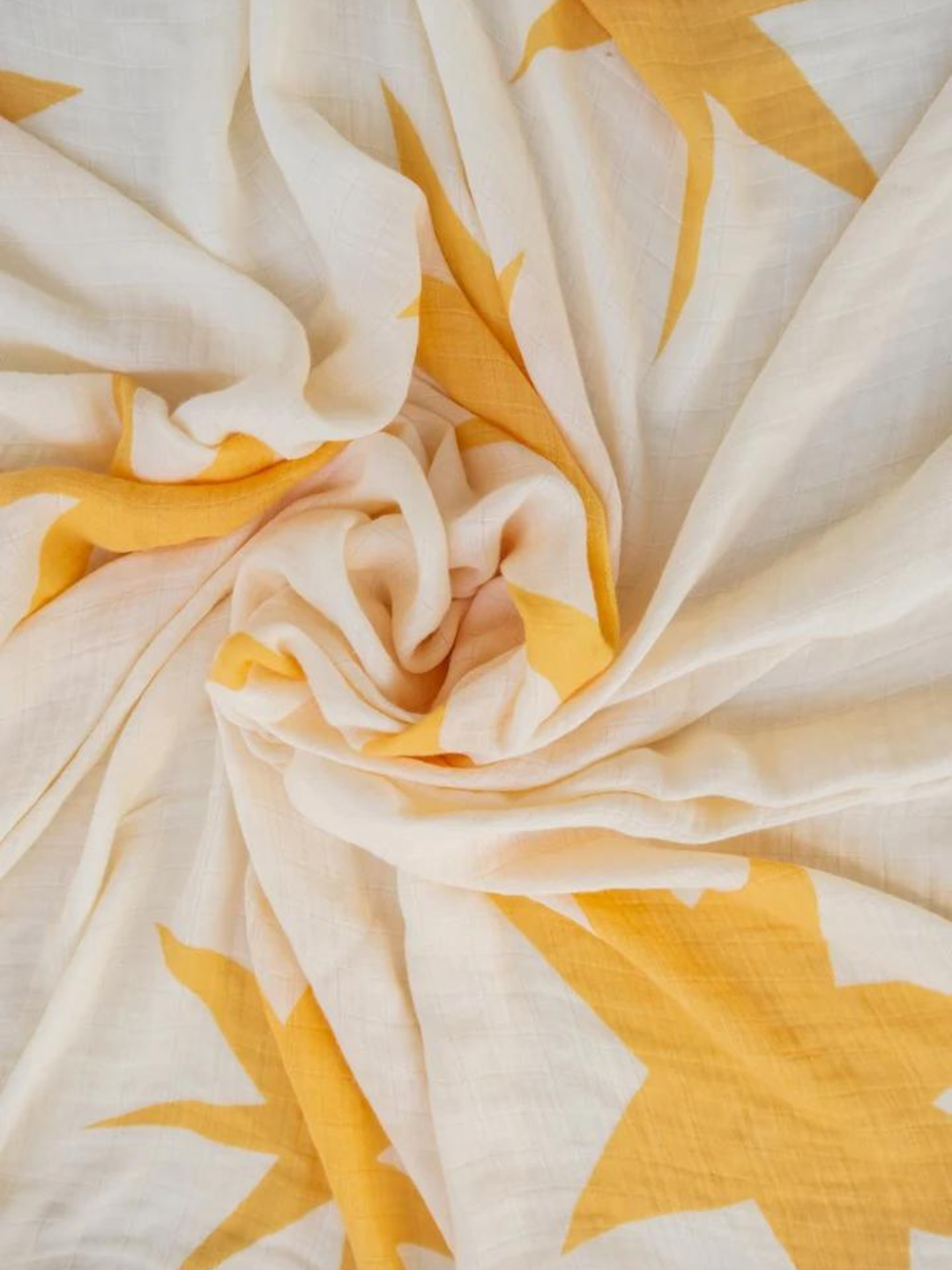 Sunburst | A white, crumpled fabric with yellow star patterns, crafted from the soft ORGANIC BAMBOO SWADDLE WRAP.