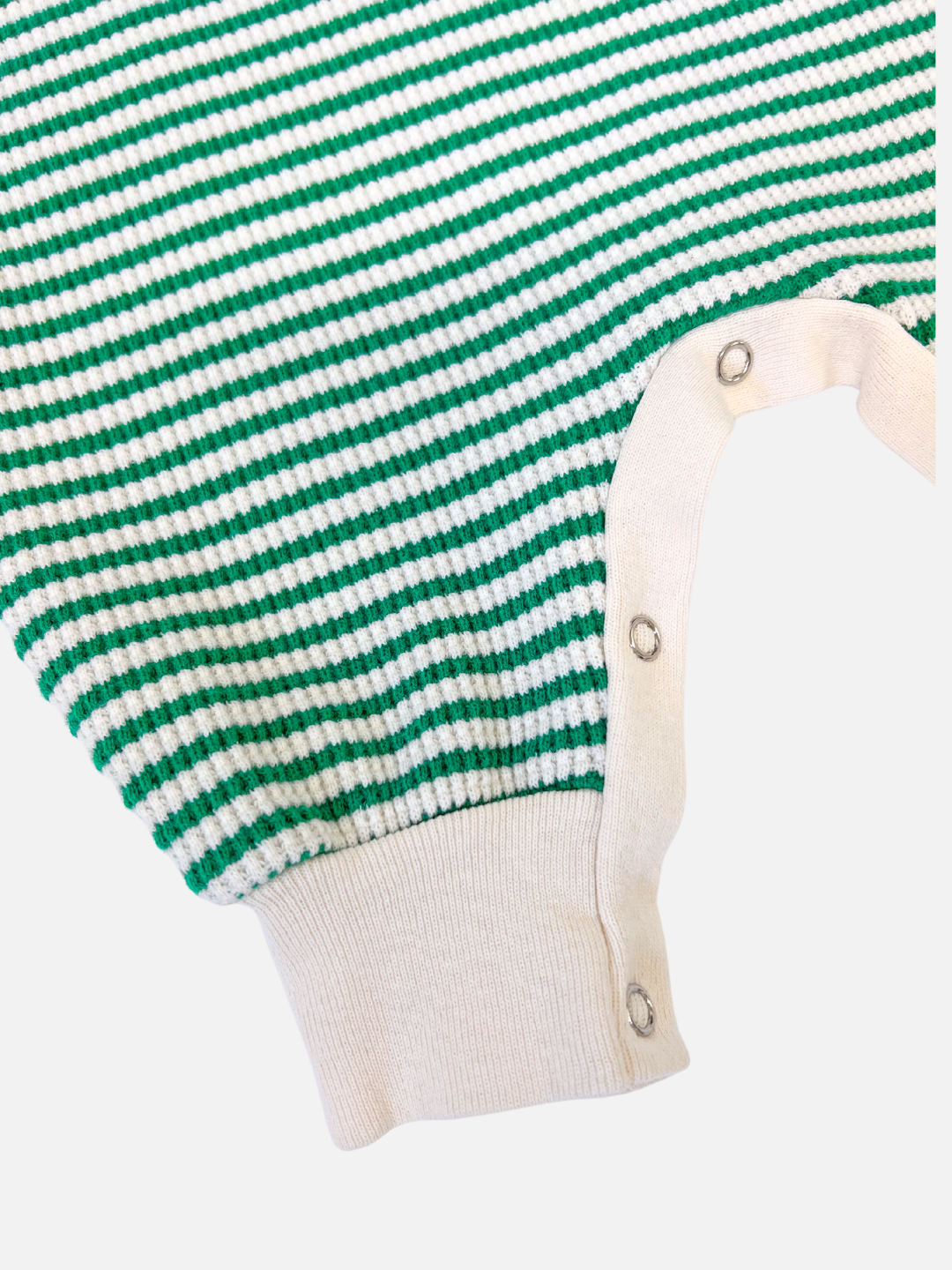 Green | Close-up of the STRIPE WAFFLE ROMPER SET, a green and white striped baby jumpsuit in waffle cotton, featuring snap buttons along a cream-colored trim.