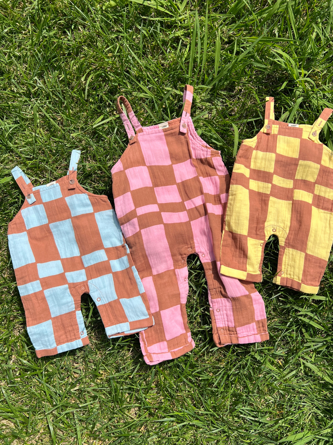Blue Checkers | Three pairs of checkered overalls on a grassy background