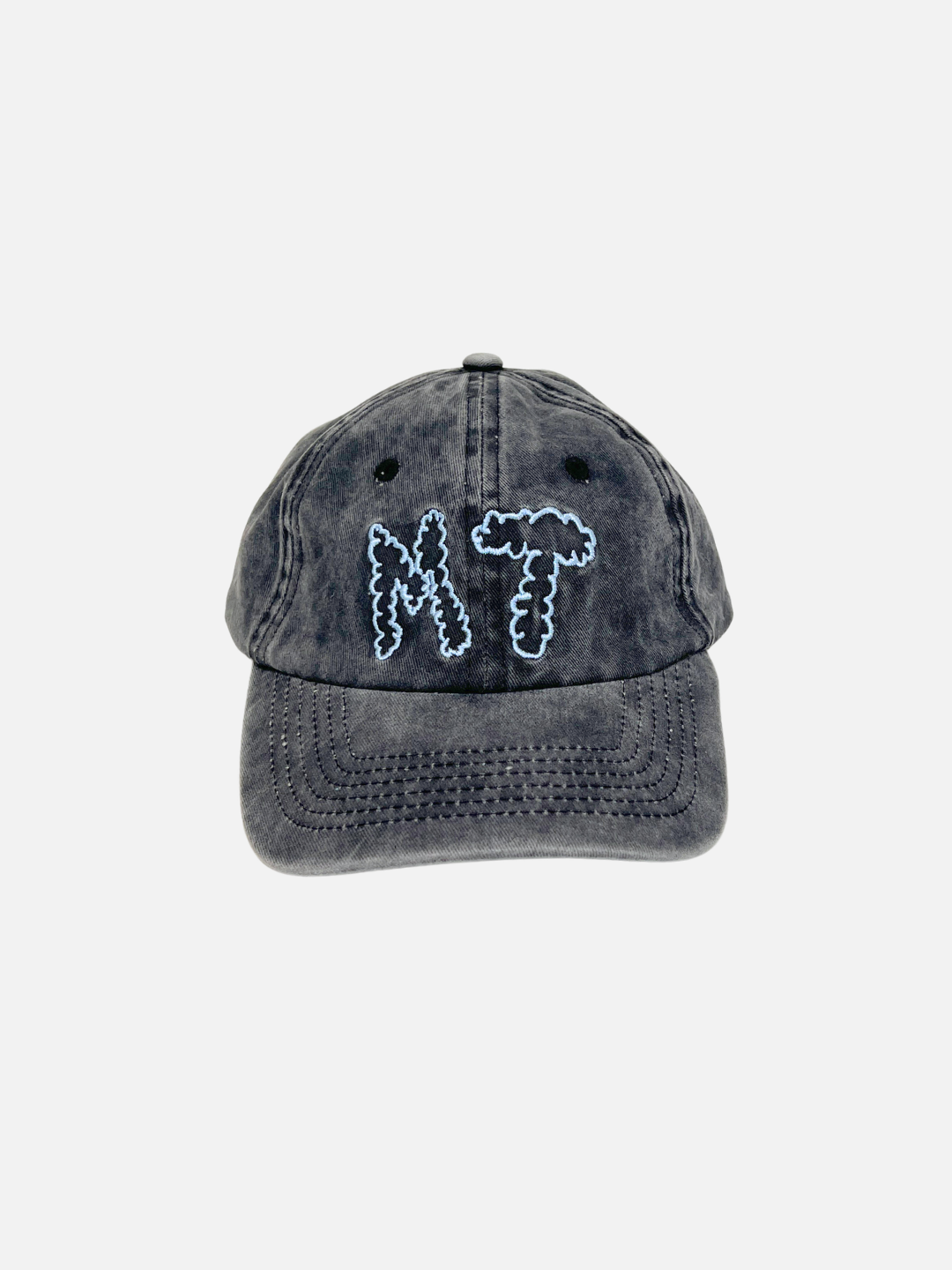 The MT DAD CAP in charcoal is a washed cotton canvas baseball cap featuring light blue embroidered "M" and "T" letters for Milk Teeth on the front, displayed against a plain white background.