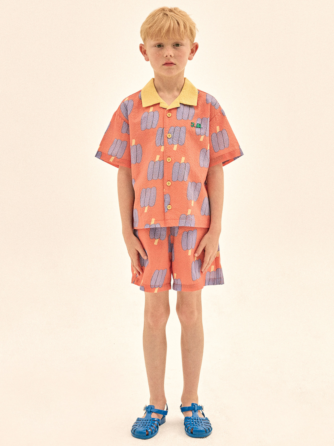 Child wearing a colorful shirt and shorts set on a beige background
