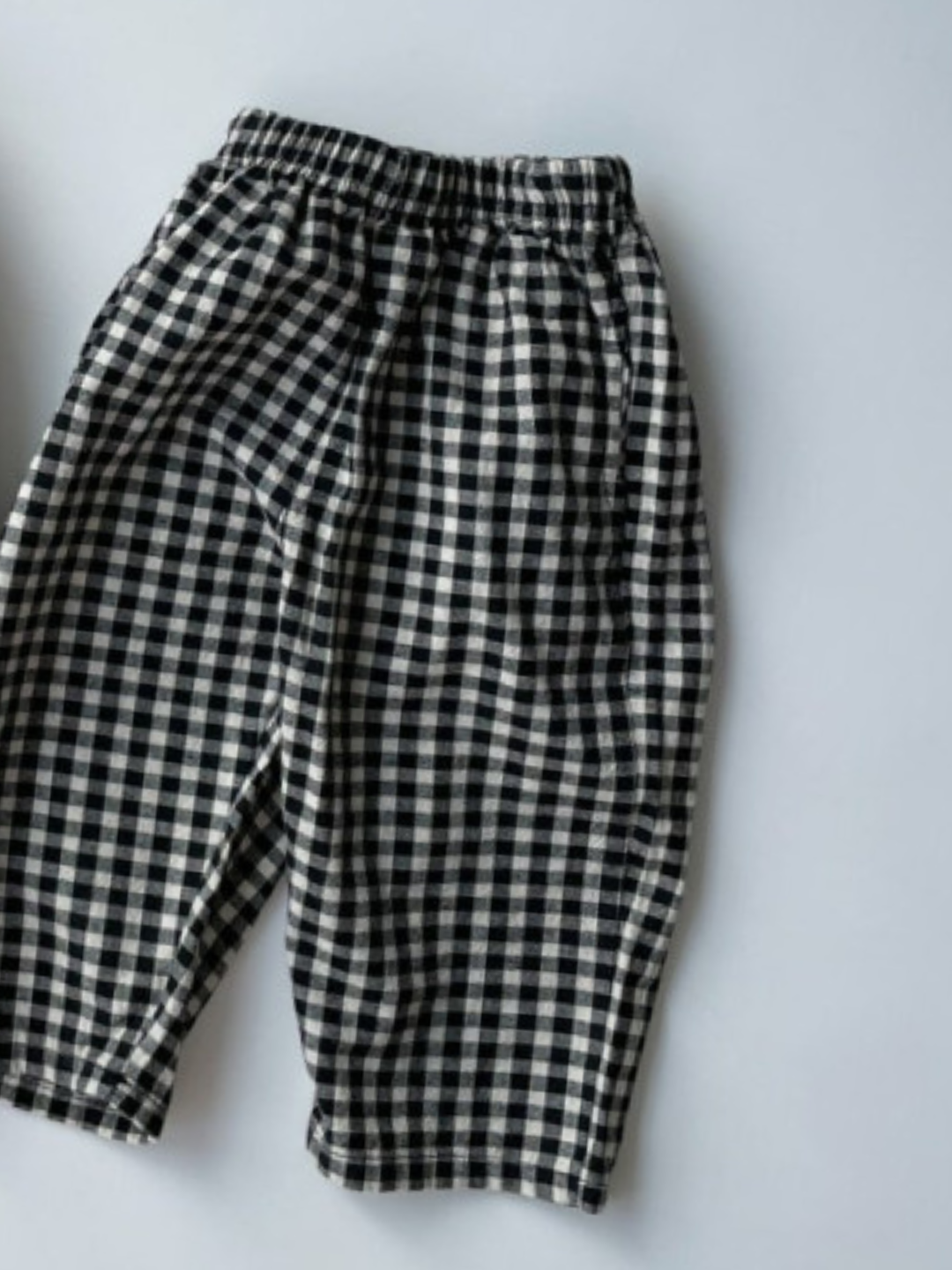 Kids black and off-white gingham check pants laid on a white background.