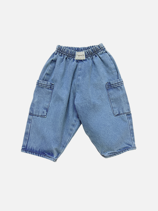Image of EMERSON DENIM BABY TROUSER: loose-fitting unisex pants crafted from organic cotton denim, featuring an elastic waistband and side pockets, shown against a white background.
