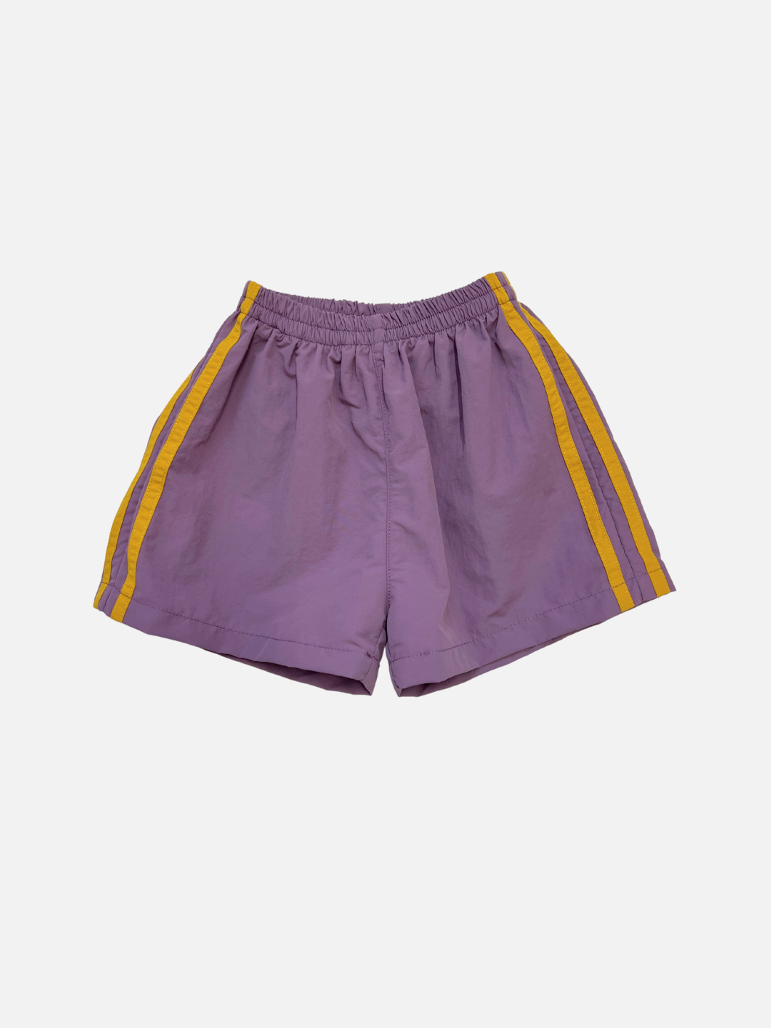 SPRINTER SHORTS in purple, featuring yellow side stripes, an elasticated waist, and a relaxed fit. Made from performance fabric and shown on a plain white background.
