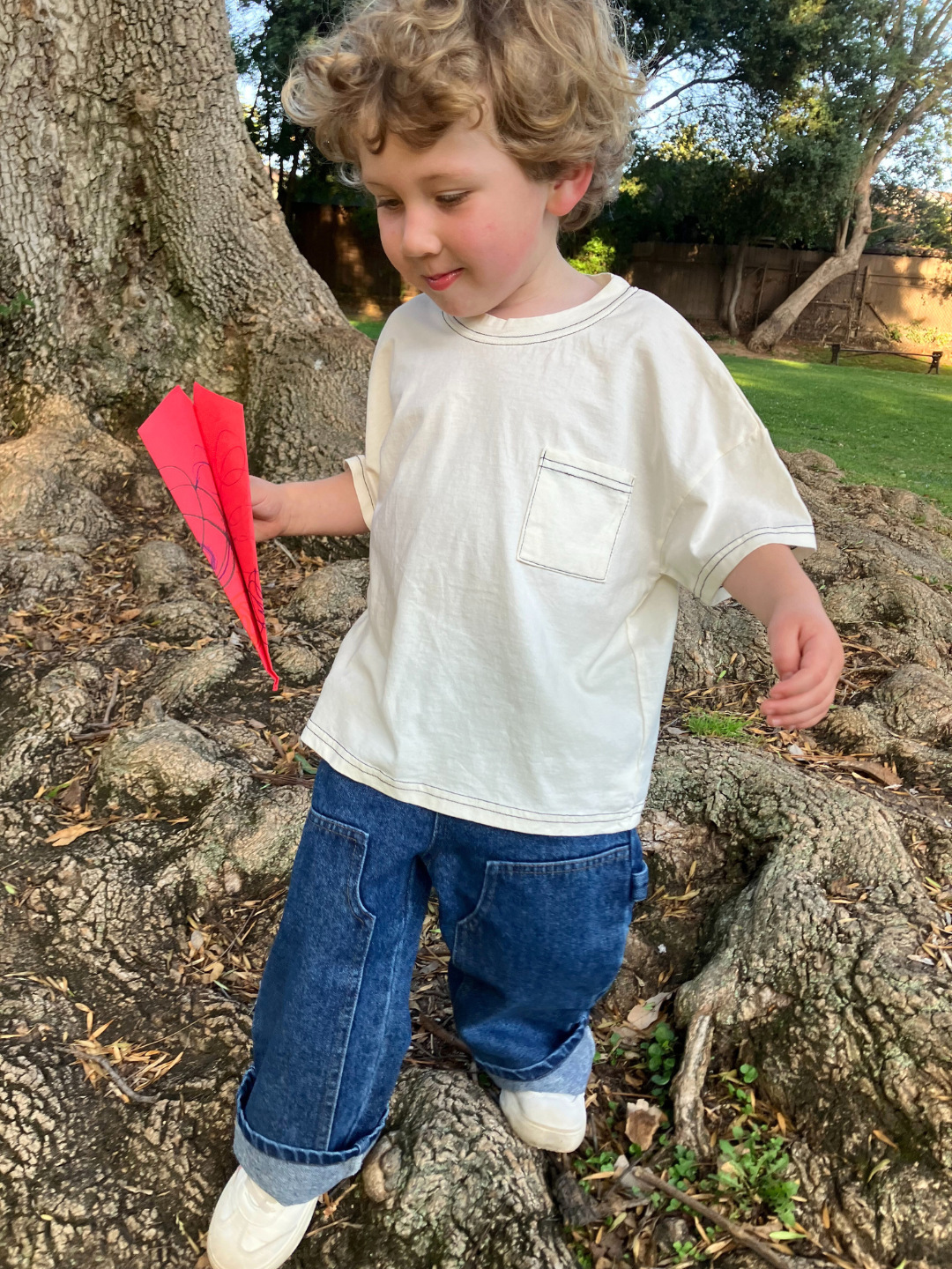 A child is wearing a Stitch Pocket Tee in Ivory with Jeans