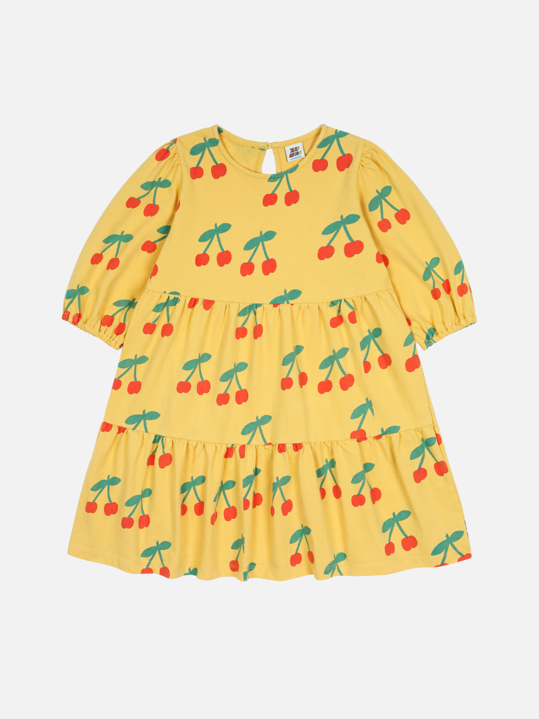 The CHERRY RUFFLE DRESS is a yellow children's dress with three-quarter sleeves, a tiered skirt, and a cherry pattern featuring red cherries and green stems on a white background.