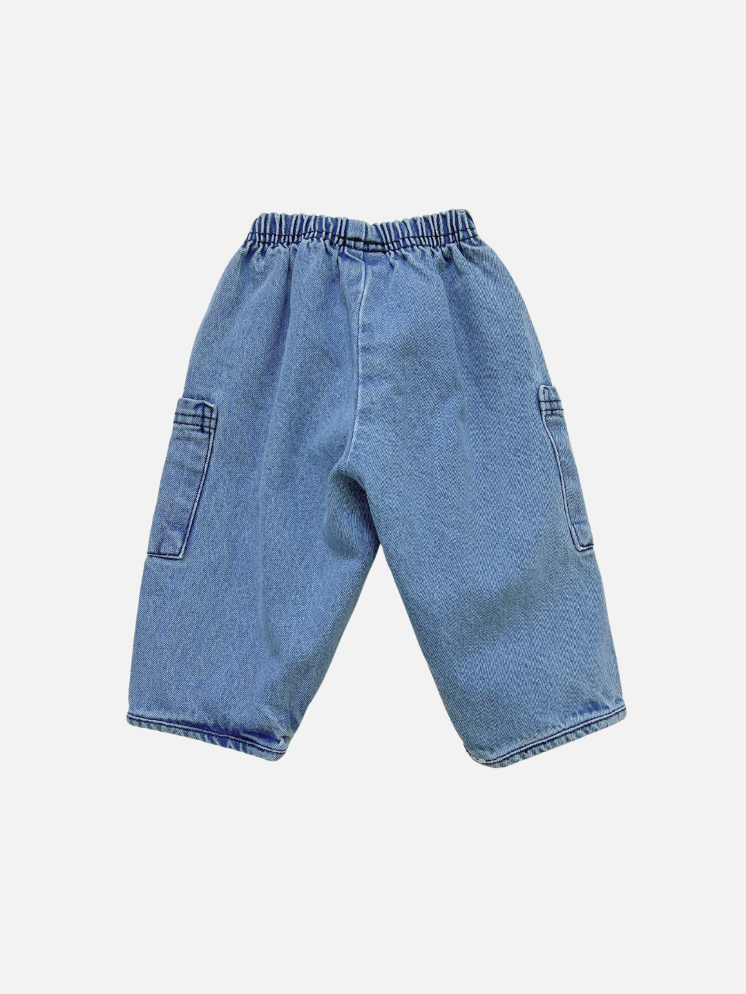 The EMERSON DENIM BABY TROUSER is a loose-fitting, unisex pant made from organic cotton denim with an elastic waistband and large side pockets, shown against a plain white background.