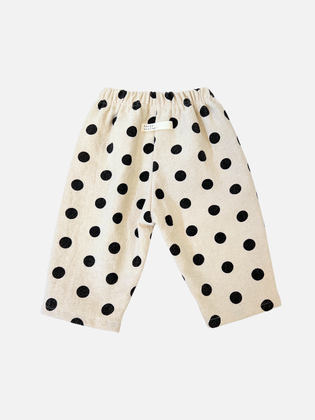 POLKA DOT PANTS are adorable ecru cotton white pants with black polka dots, featuring an elastic waistband. These trendy pull-on pants from a Korean baby brand are presented on a plain white background.