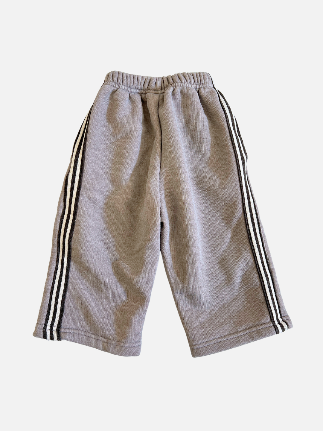 The ALL DAY PANT, in gray and designed with a relaxed fit, is crafted from brushed cotton fleece. It features black and white side stripes and an elastic waistband, shown laid flat on a plain background.