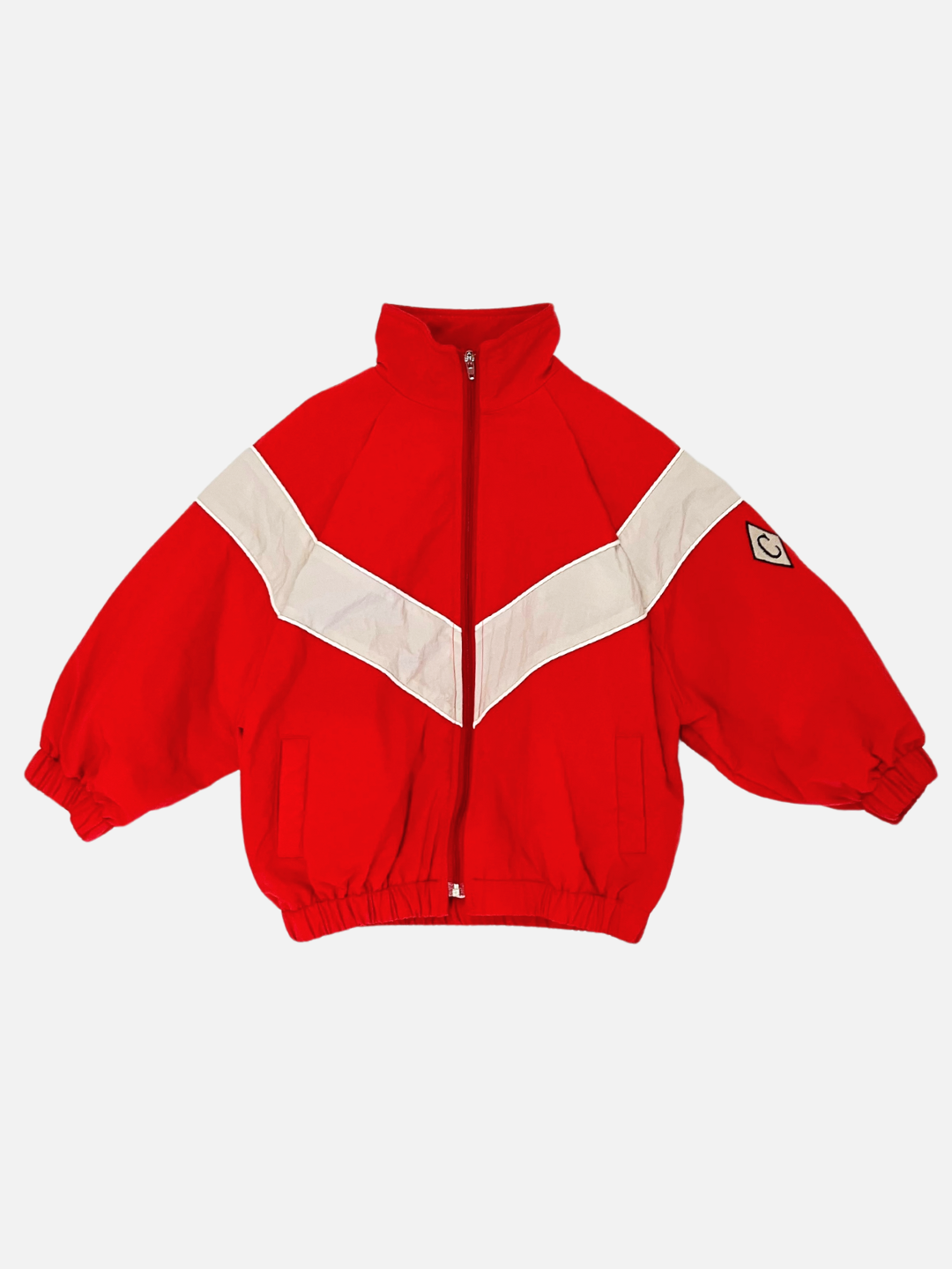 Red | The WARM-UP JACKET in vibrant red is a retro track jacket featuring a white V-shaped stripe across the chest and arms. It boasts an elastic waistband and cuffs, along with a small patch on the left sleeve—making it the perfect lightweight layer for any occasion.