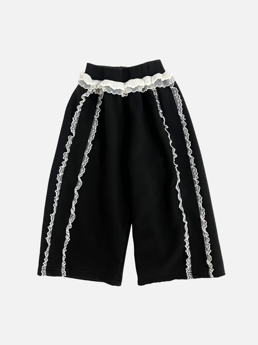 Image of Front view of kid's Relay pants in black with  white ruffles at the waist and down both legs