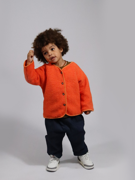 Second image of Tangerine | Front view of a kids orange collarless fleece jacket with four brown buttons.