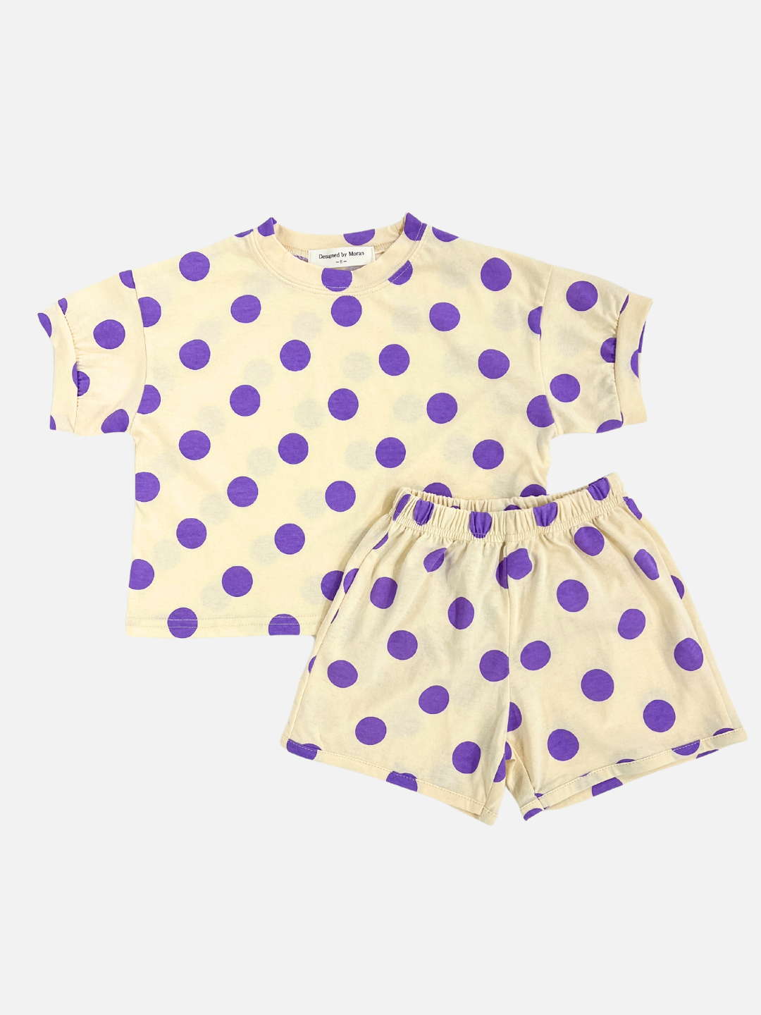 A kids' tee shirt and shorts set in a pattern of purple dots on an ecru background