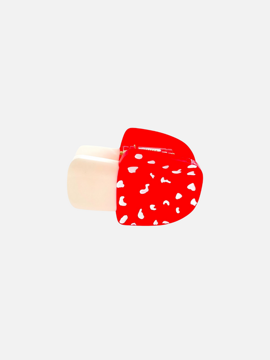 Image of The MINI MUSHROOM HAIR CLAW features a red and white patterned design, crafted from biodegradable cellulose acetate, set against a plain white background.