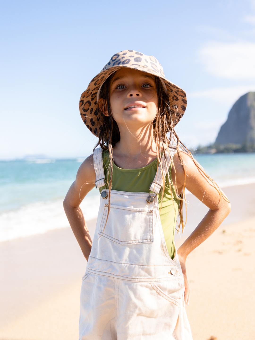 A child is wearing Calico Crab Bucket Hat at the beach