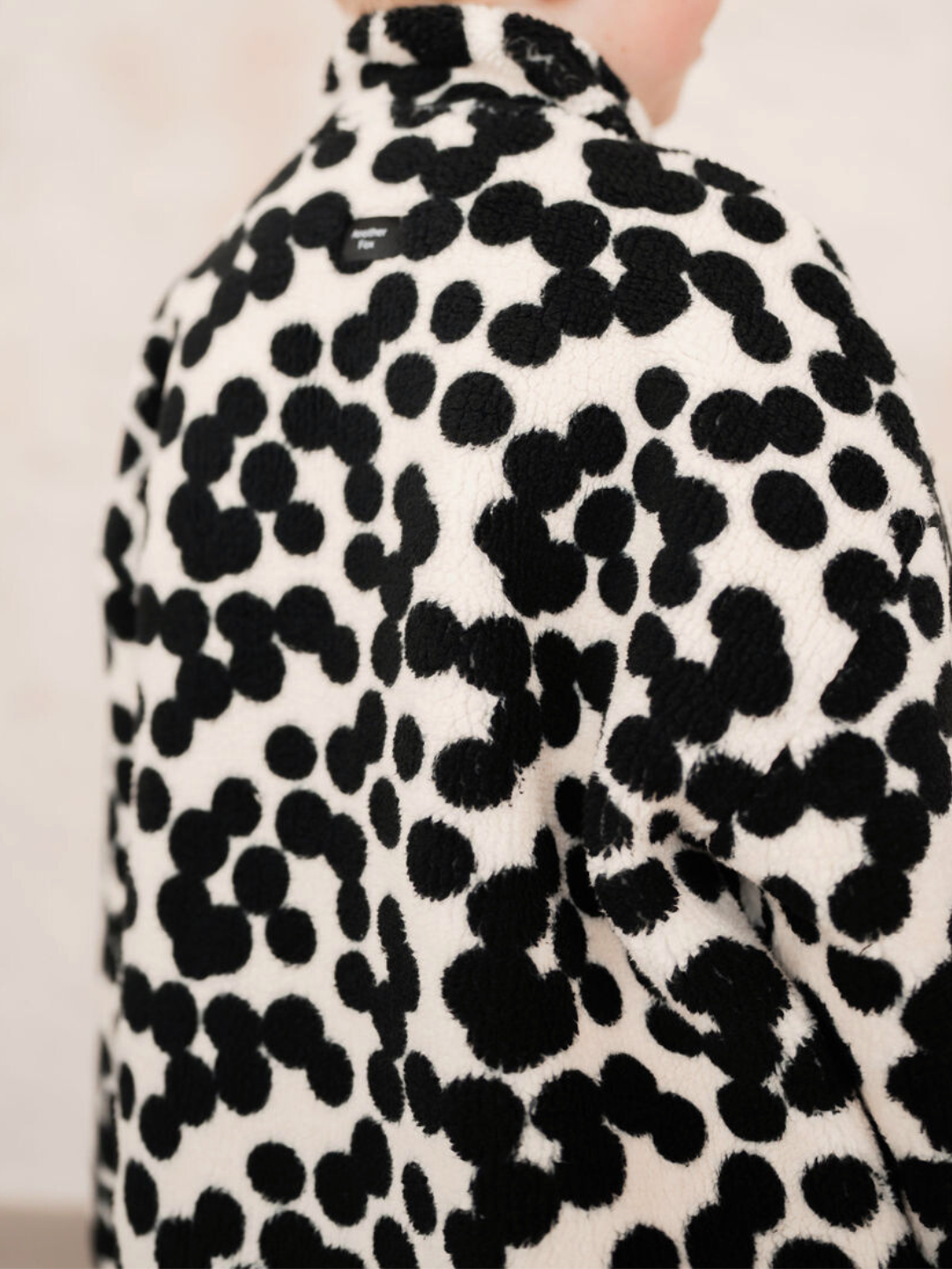 A person wearing the SPOT FUNNEL COAT, featuring black and white spots, is shown from the back—ideal for those browsing baby and new arrivals.