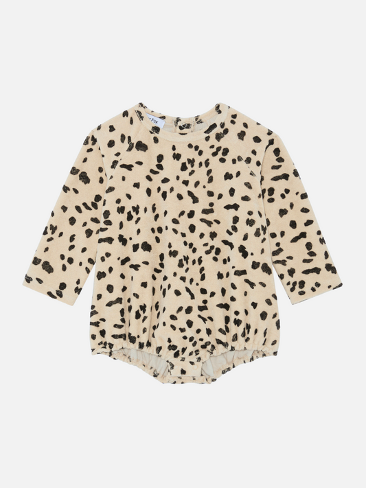 Image of Discover our new arrivals: the DALMATIAN TERRY BODYSUIT, a beige long-sleeve baby onesie with a black spotted pattern, resembling animal print. Shop all clothing to find more adorable outfits for your little one.