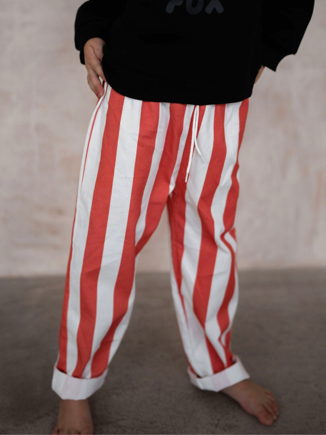 Person wearing RED BLOCK STRIPE PANT with a black top, standing on a gray floor. Face and upper body are not visible—perfect for those seeking to explore new arrivals in our shop all clothing section.