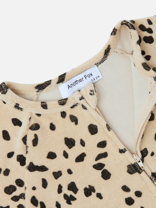 Second image of The DALMATIAN TERRY SLEEPSUIT is a beige baby onesie with black speckles, featuring long sleeves, a front zipper, and cuffs at the sleeves and ankles. It's perfect for your baby and new arrivals section—be sure to check the price during your next merchandising review.