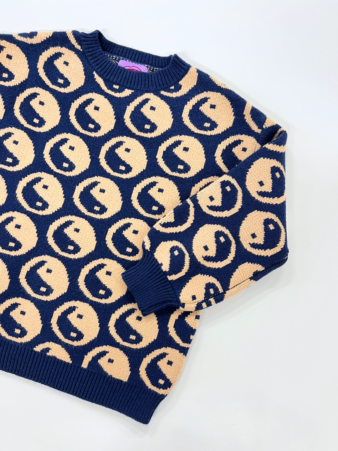 Navy | The COSMOS SWEATER is a super-soft, long-sleeved crewneck sweater with a navy blue base and an intarsia knit pattern of cream yin yangs.