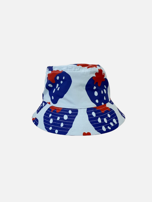 Image of The STRAWBERRY BUCKET HAT features a bold blue strawberry print with dark red accents. Made from sustainable materials, it's perfect for a day at the shore or casual outings.