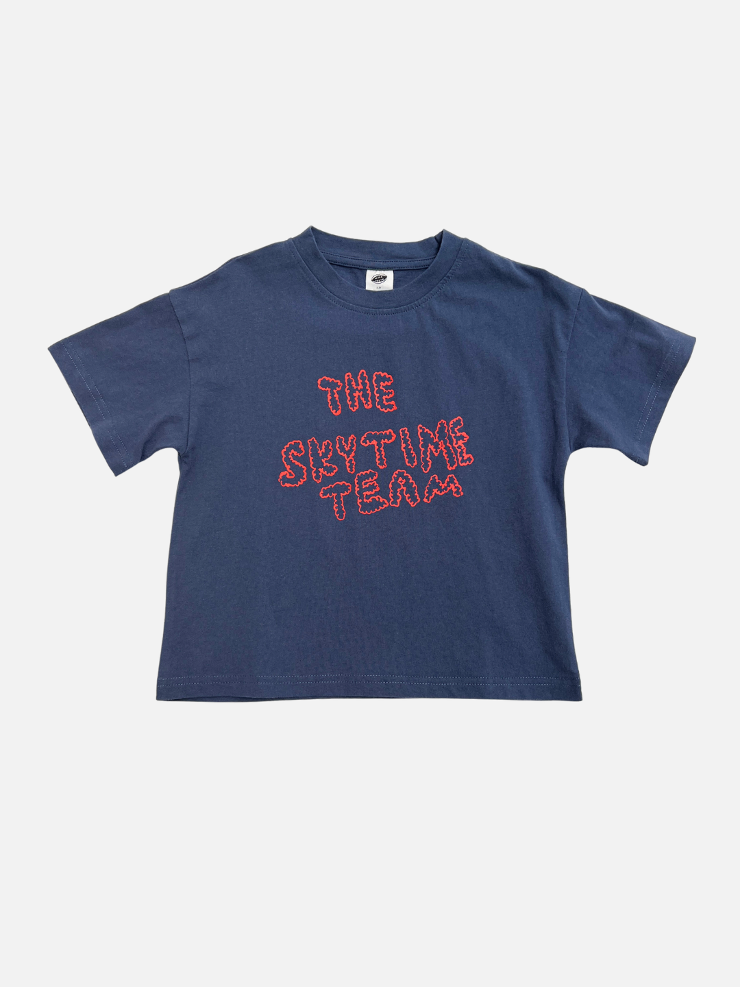 The SKYTIME TEE is a blue short-sleeve shirt featuring "THE SKYTIME TEAM" in wavy red outline on the front, designed by artists as part of our unique Milk Teeth tees collection.