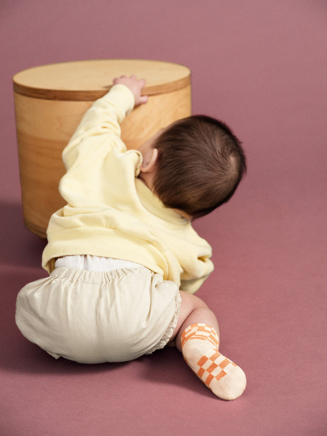 A baby wearing a pair of kids' ankle socks in a peaches and cream check