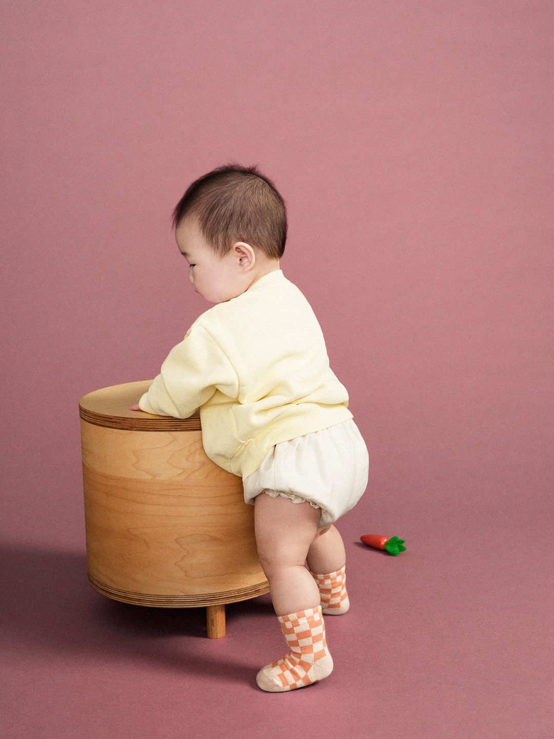 A baby wearing a pair of kids' ankle socks in a peaches and cream check