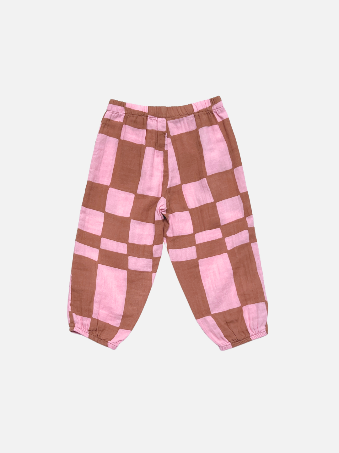 The MUSLIN PULL ON PANT is a loose-fitting toddler jogger with an elastic waistband and cuffs, crafted from organic cotton muslin in a pink and brown checkerboard print, shown against a white background.