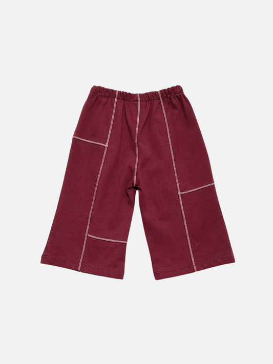 Image of Maroon | TOPSTITCH BABY PANT in maroon, featuring a wide-leg cotton design, white contrast stitching, and an elastic waistband, displayed on a flat white background.