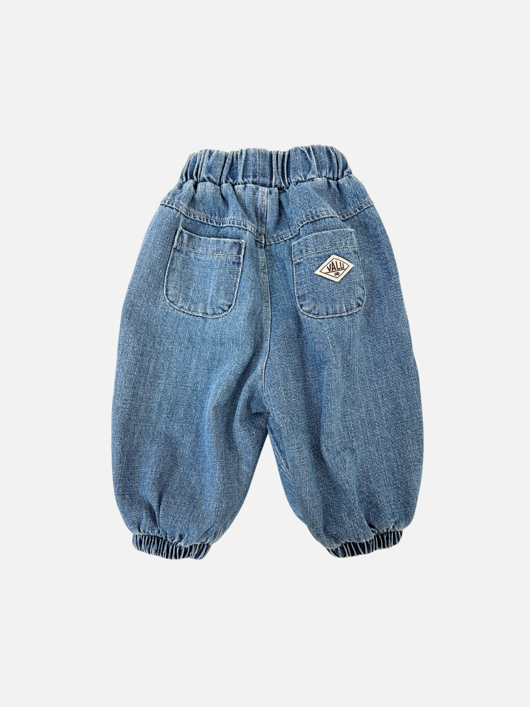 Denim | Valu Baby offers the BALLOON JEAN, blue denim baby joggers with an elastic waistband and cuffs. Stylishly designed with a single back pocket and a diamond-shaped patch on the rear right side.