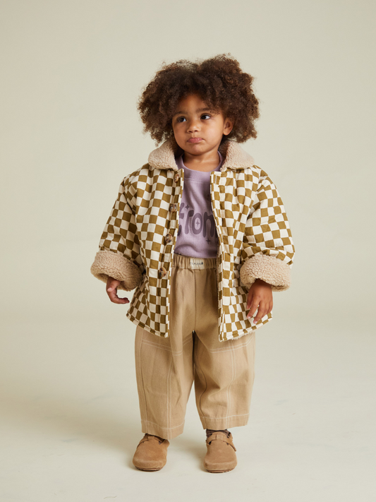Second image of The EMERY COCO CHECKERBOARD COAT is a unisex short-sleeve button-up jacket with a brown and white checkerboard pattern, tan sherpa collar, rolled cuffs, and crafted from cotton for stylish outerwear.