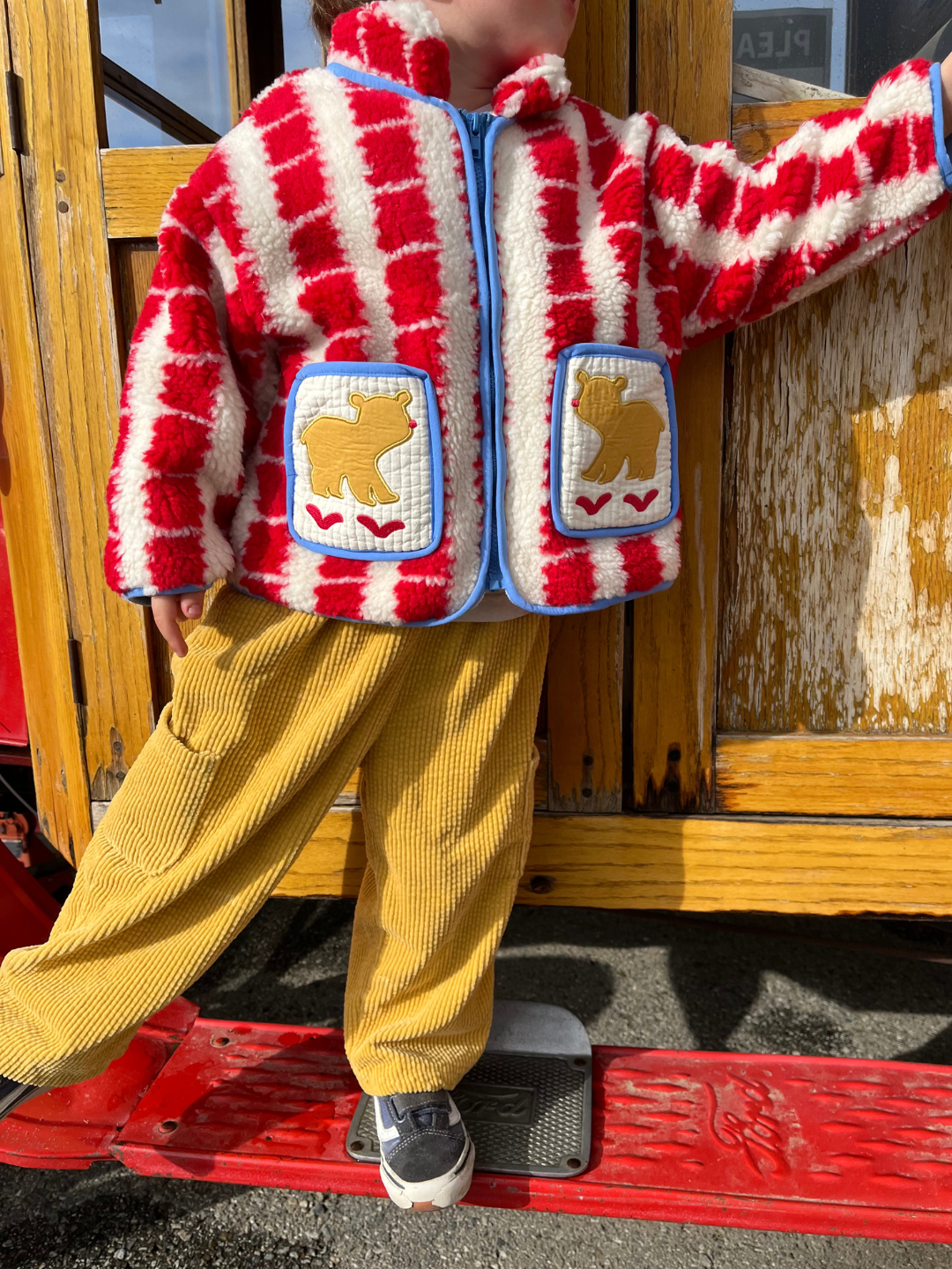 Gold | A child wearing a red and white striped fluffy jacket with adorable bear patches and the trendy Korean kids brand's CORD POCKET PANT in yellow corduroy stands near a wooden surface.