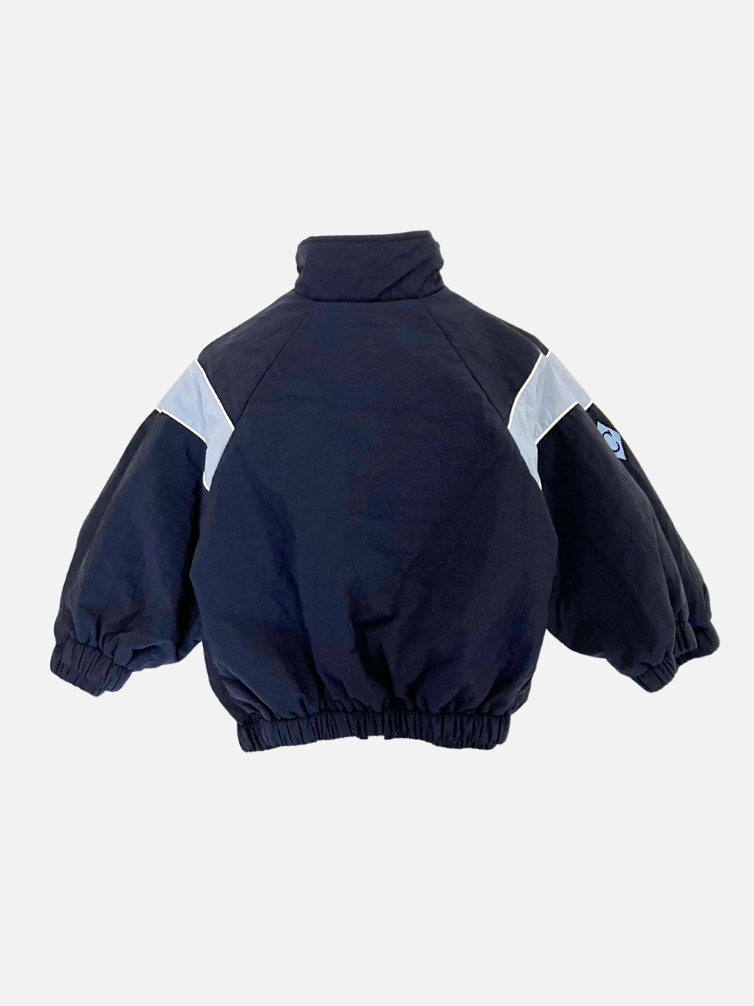 Navy | The WARM-UP JACKET, a black and white puffer with a high collar and elastic cuffs, evokes the style of a retro track jacket. This piece from the Korean label is displayed against a plain white background with its back showcased.