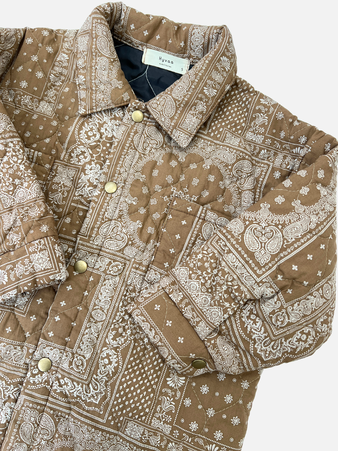 Close up on the kid's Bandana Quilted Overshirt highlighting the gold buttons and print