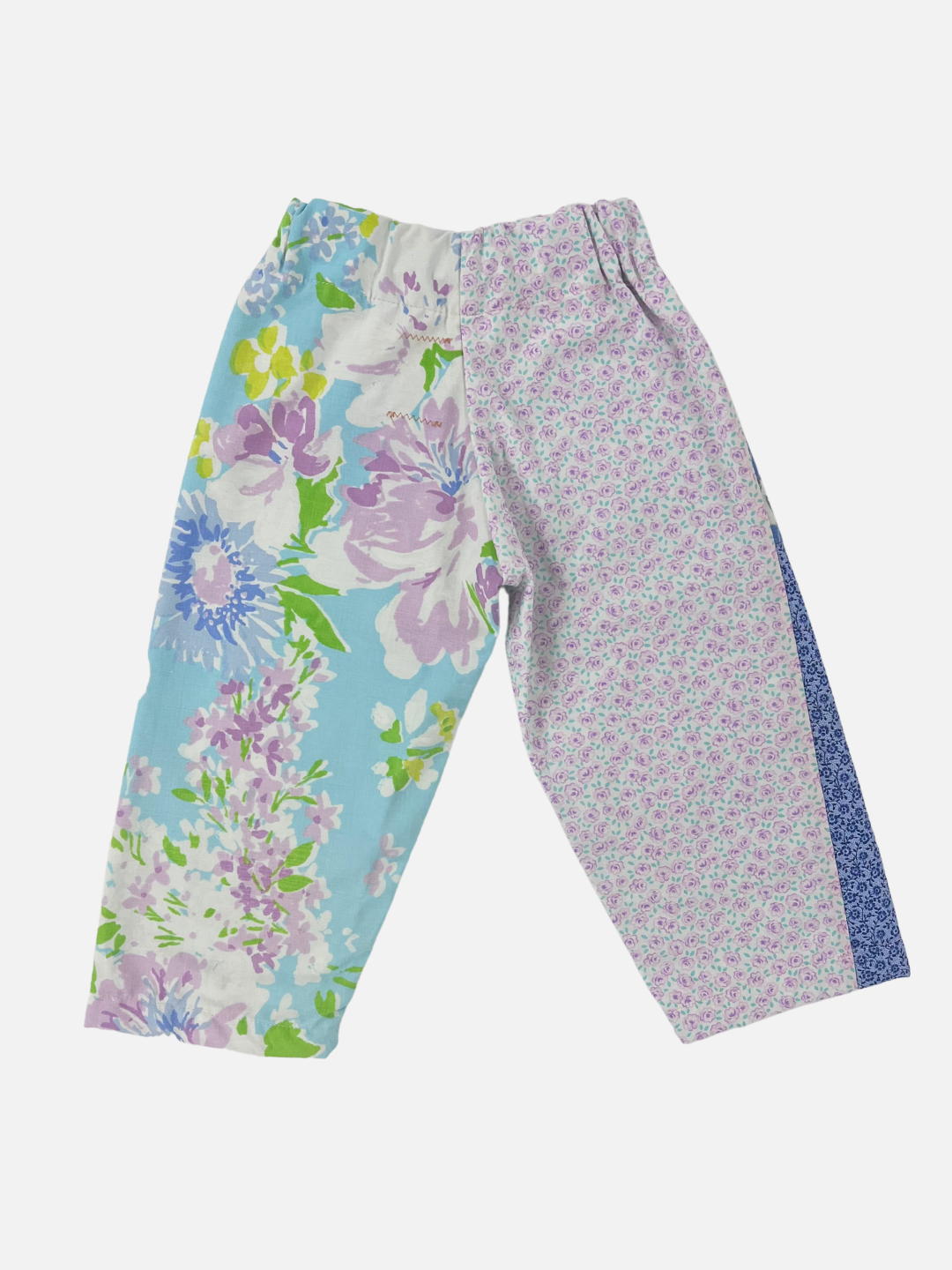 Front view of kid's patchwork pant. Left leg - small flowers on blue, big pink and blue flowers. Right Leg - Flowers on light blue background.