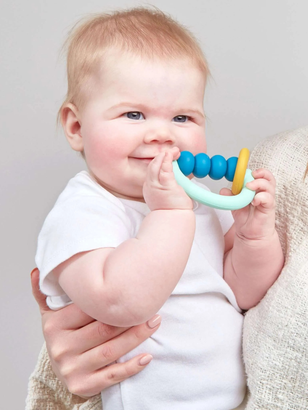A child is holding a Pacific 2.0 Teether