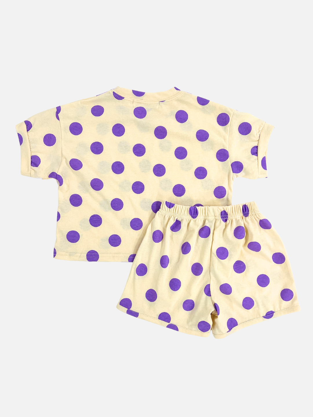 A kids' tee shirt and shorts set in a pettern of purple dots on an ecru background, back view