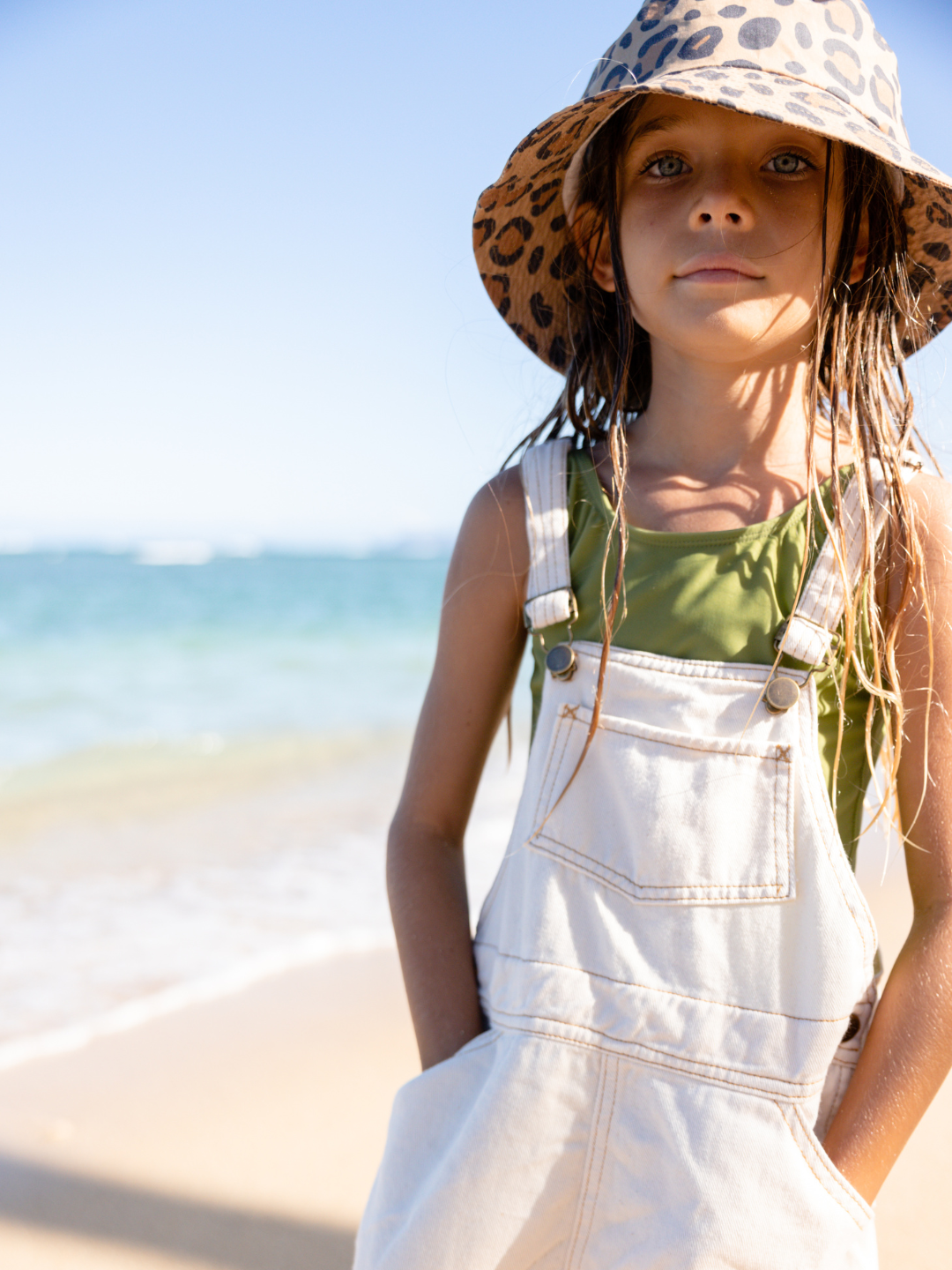 A child is wearing Calico Crab Bucket Hat at the beach