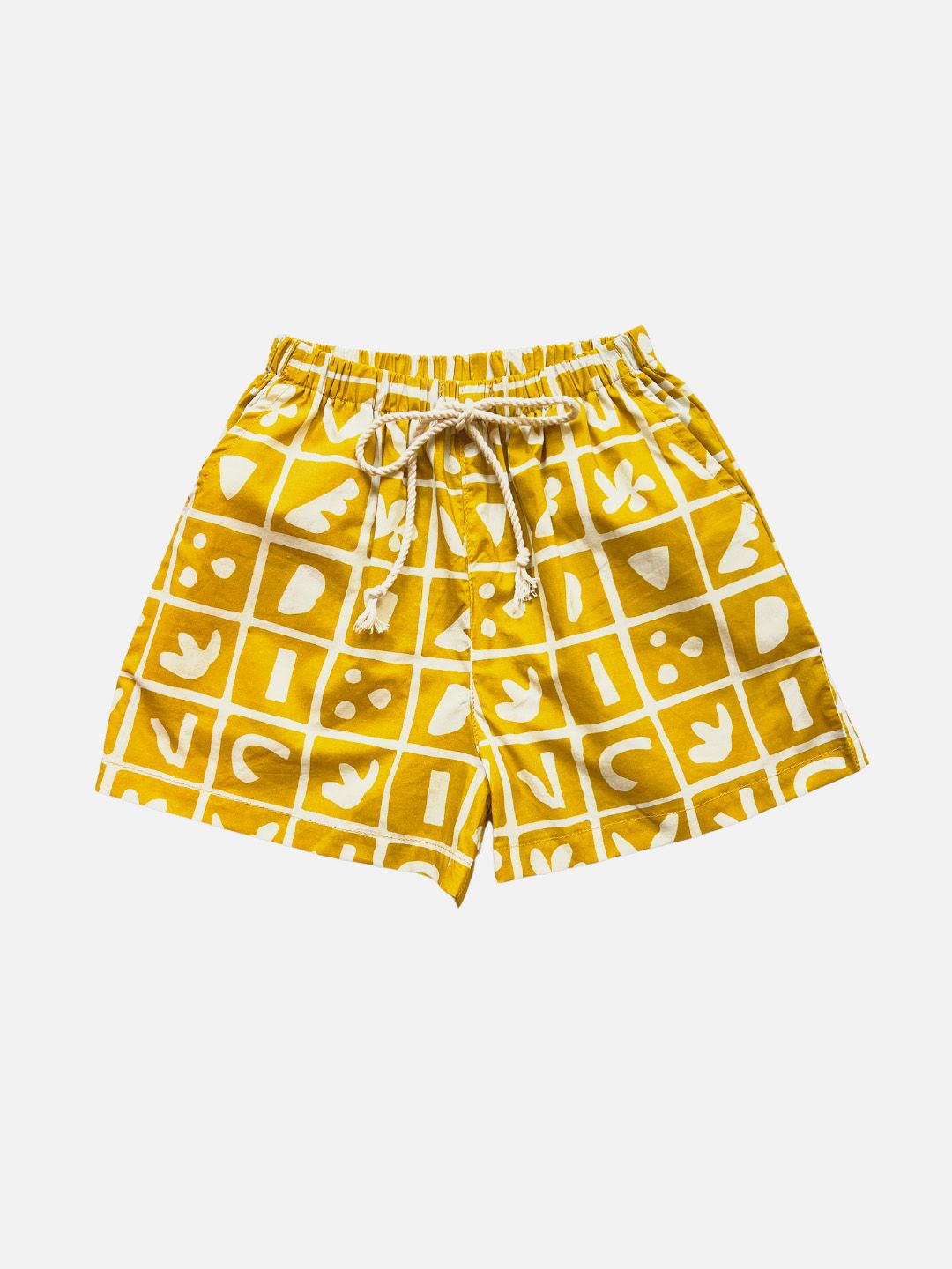 A pair of kids' shorts in mustard yellow overlaid with a grid of different shapes in white