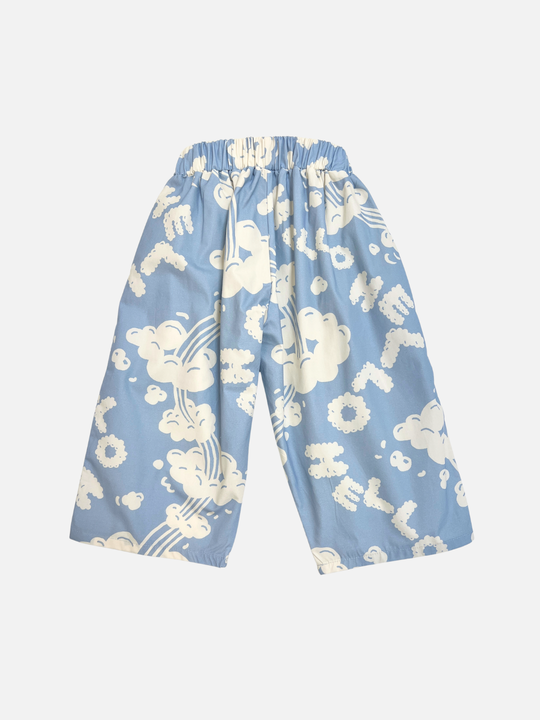 The SKYWRITING PANT features light blue wide legs, an elastic waistband, and is decorated with playful white cloud and rainbow patterns plus scattered white text.
