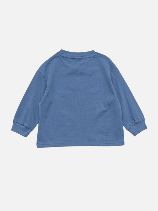 Second image of Blue | The SQUIGGLE LONGSLEEVE is a blue relaxed-fit longsleeve tee crafted from 100% cotton, featuring a simple white abstract outline graphic of a face on the front, reminiscent of a doodle character, and displayed against a plain background.