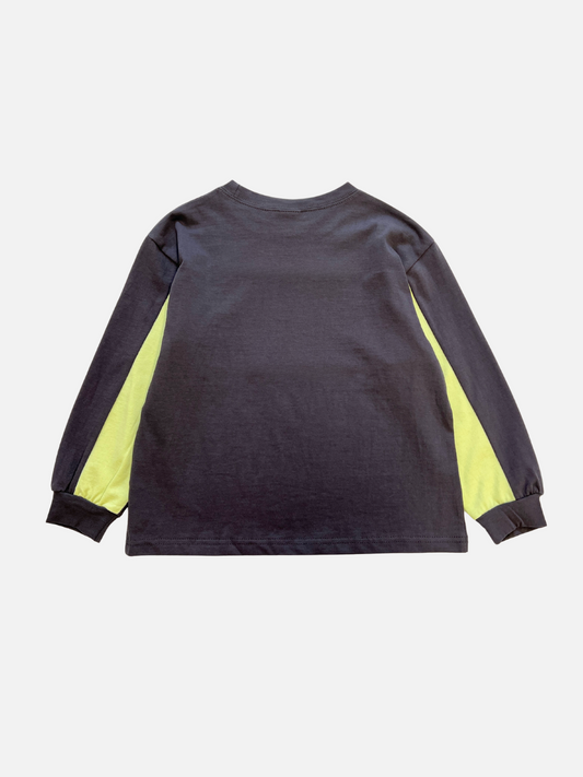 Second image of The RACING LONGSLEEVE is a black kids’ crewneck tee with long sleeves, yellow chest stripe, white “FORMULA 1” text, and racing graphics. Made from soft cotton jersey by a top Korean kids' brand.