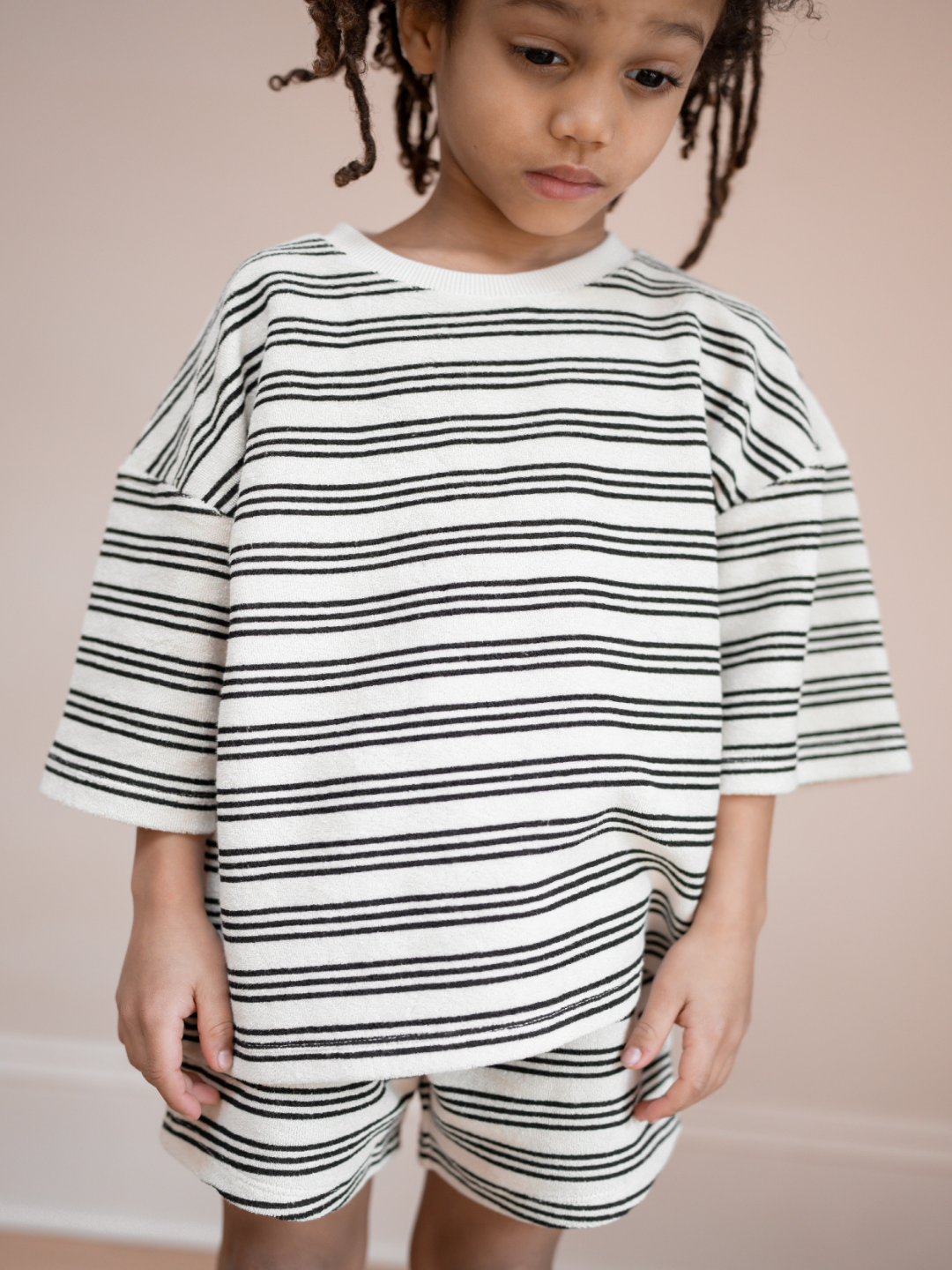 A child is wearing matching set of stripe Terry towel shorts & tee
