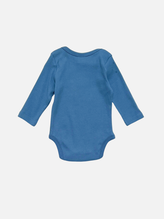 Second image of The DOMINO LONG SLEEVE ONESIE in blue is a soft ribbed cotton bodysuit with long sleeves, featuring a playful white smiley domino graphic on the front, shown against a white background.
