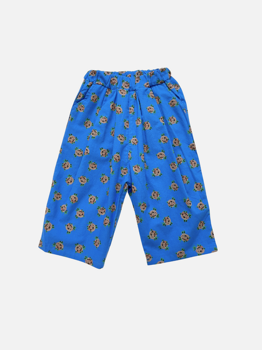 Image of ROSETTE PANTS: Blue wide-leg cotton poplin trousers featuring an elastic waistband and all-over floral screen-print, from a stylish Korean kids label. Displayed on a plain white background.