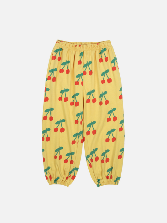 Image of The CHERRY PUFFY PANTS are yellow with an elastic waistband and cuffs, adorned with red cherries and green stems.