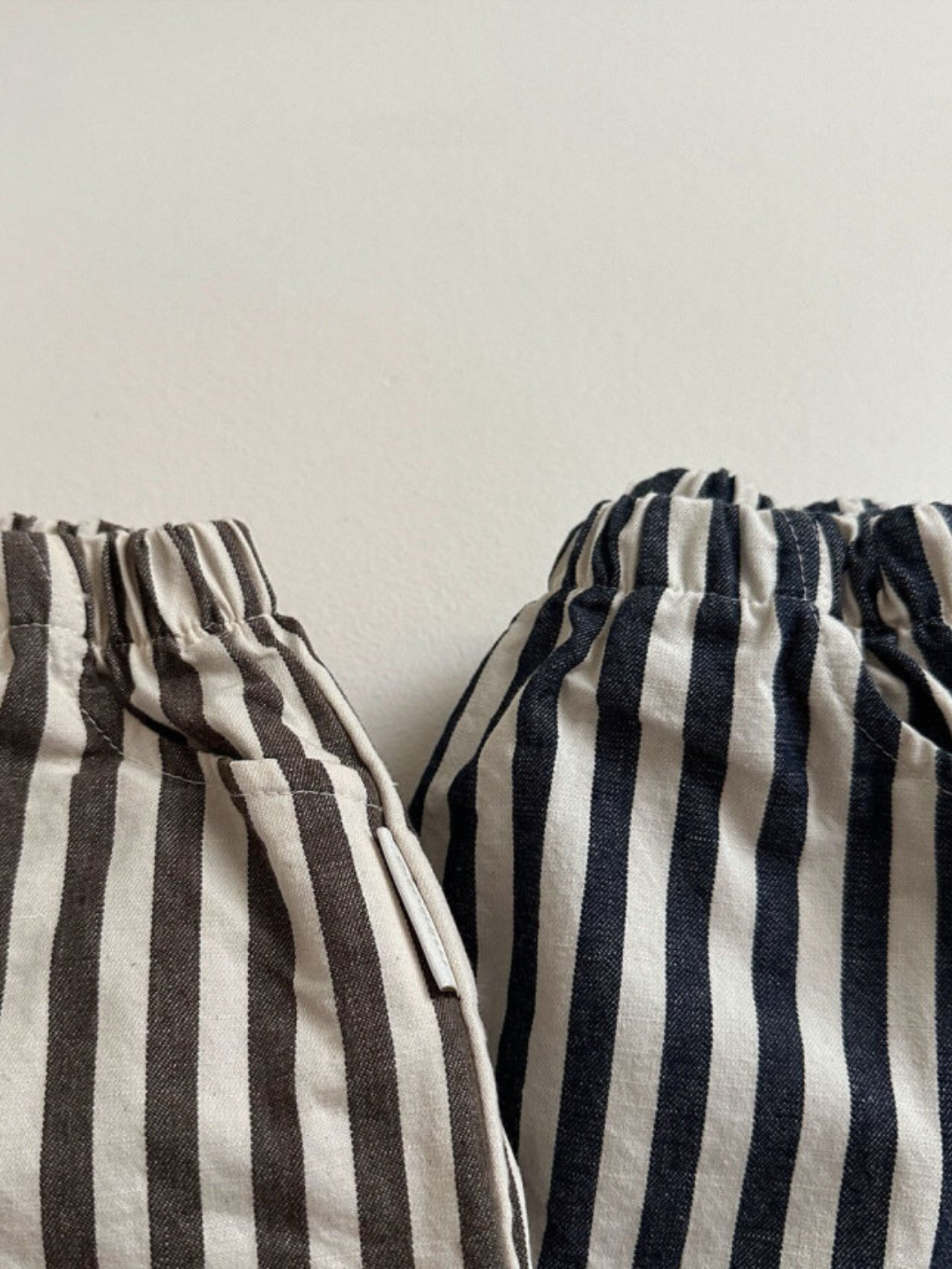 Charcoal Stripe | Two pairs of PIRATE PANTS by Minirobe, each featuring bold stripes with elastic waists—one pair in black and white and the other in navy and white—set against a plain white background. Both pairs showcase stylish balloon legs for added flair.