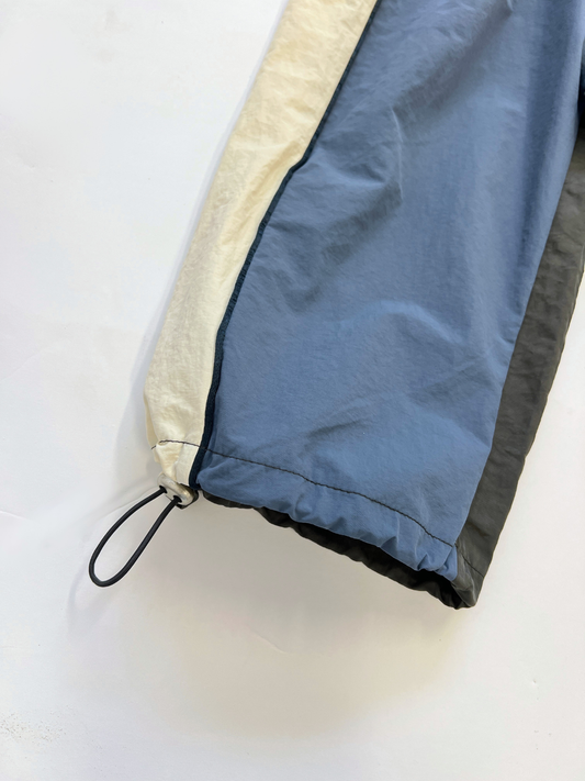 Second image of The WARM-UP PANT features blue front panels, off-white sides, black back panels, and elastic waistband and cuffs—ideal for a sporty look inspired by top Korean kids brands.