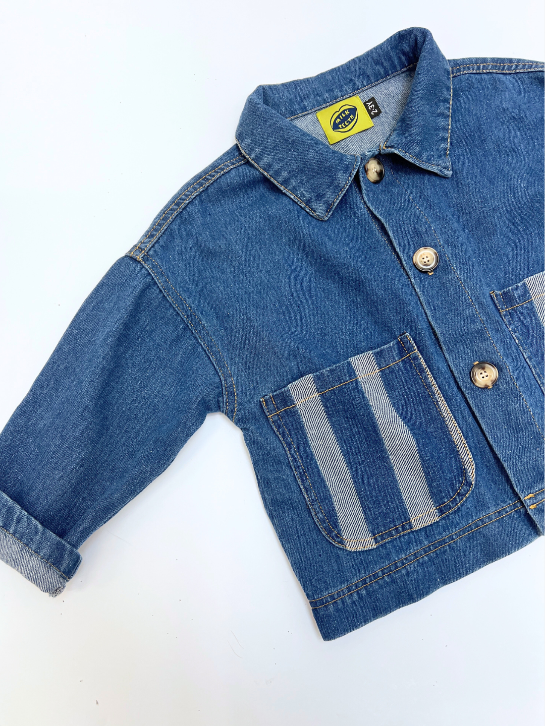 Blue denim jacket with a striped pocket on a white background